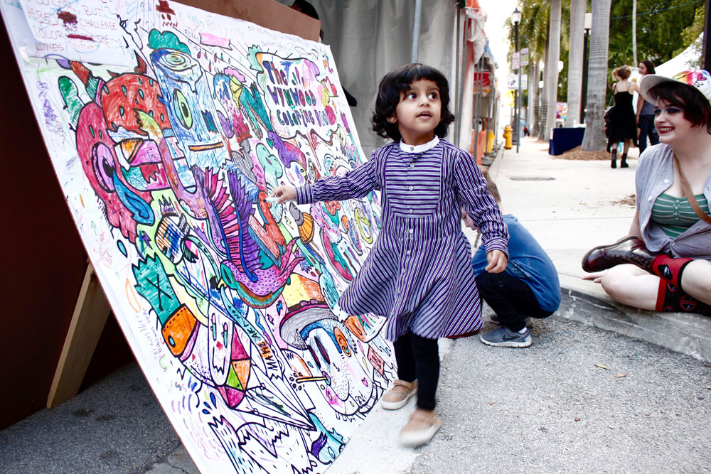 A littler girl painting on an interactive mural.