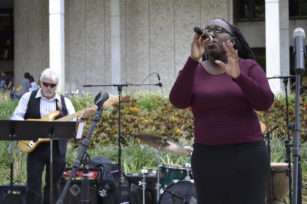 A student singing in front of Koffee House at Kendall Campus.