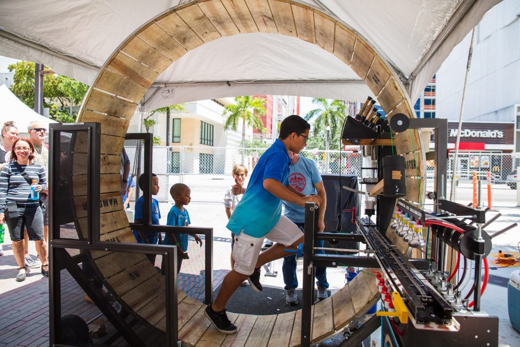 A young boy on a life-size hamster wheel.