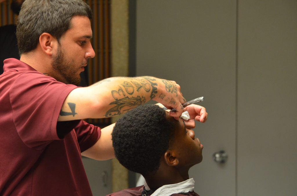 Barber giving student haircut.
