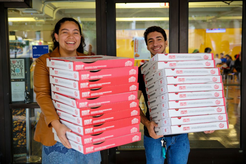 Students carrying boxes of pizza.
