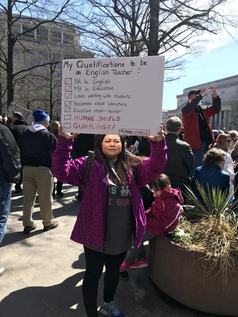 Teacher holding up her protest sign.