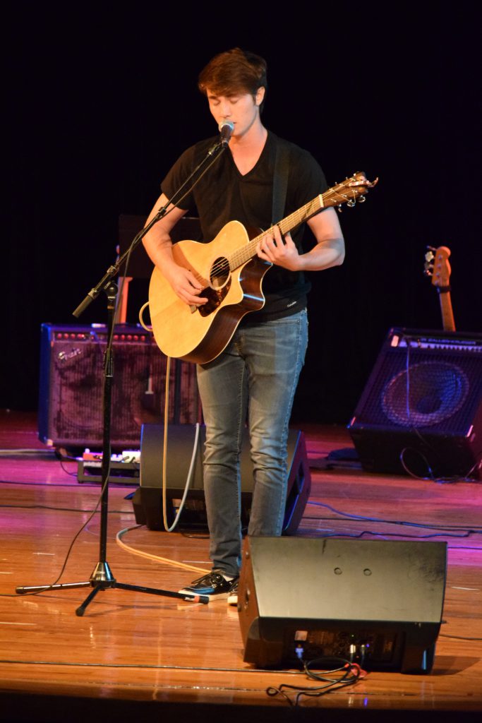 Student playing his guitar on stage.