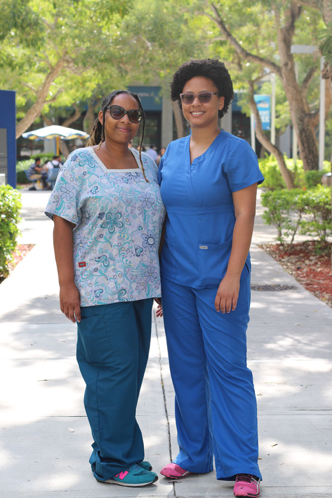 Mother and daughter posing for the camera wearing their nurse scrubs.