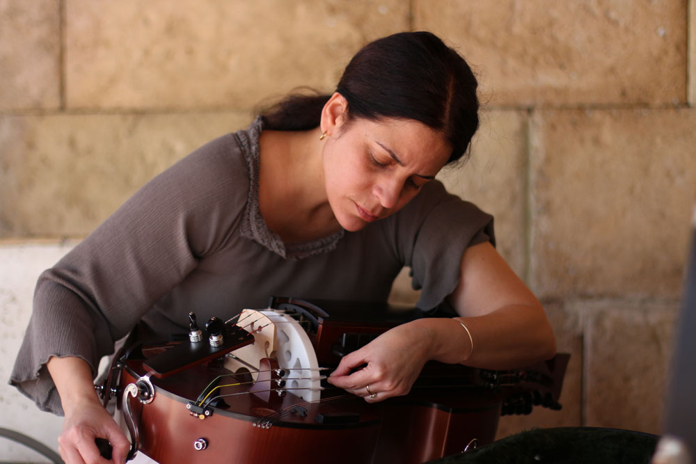 Beatriz tuning her Hurdy-gurdy, a medieval instrument.